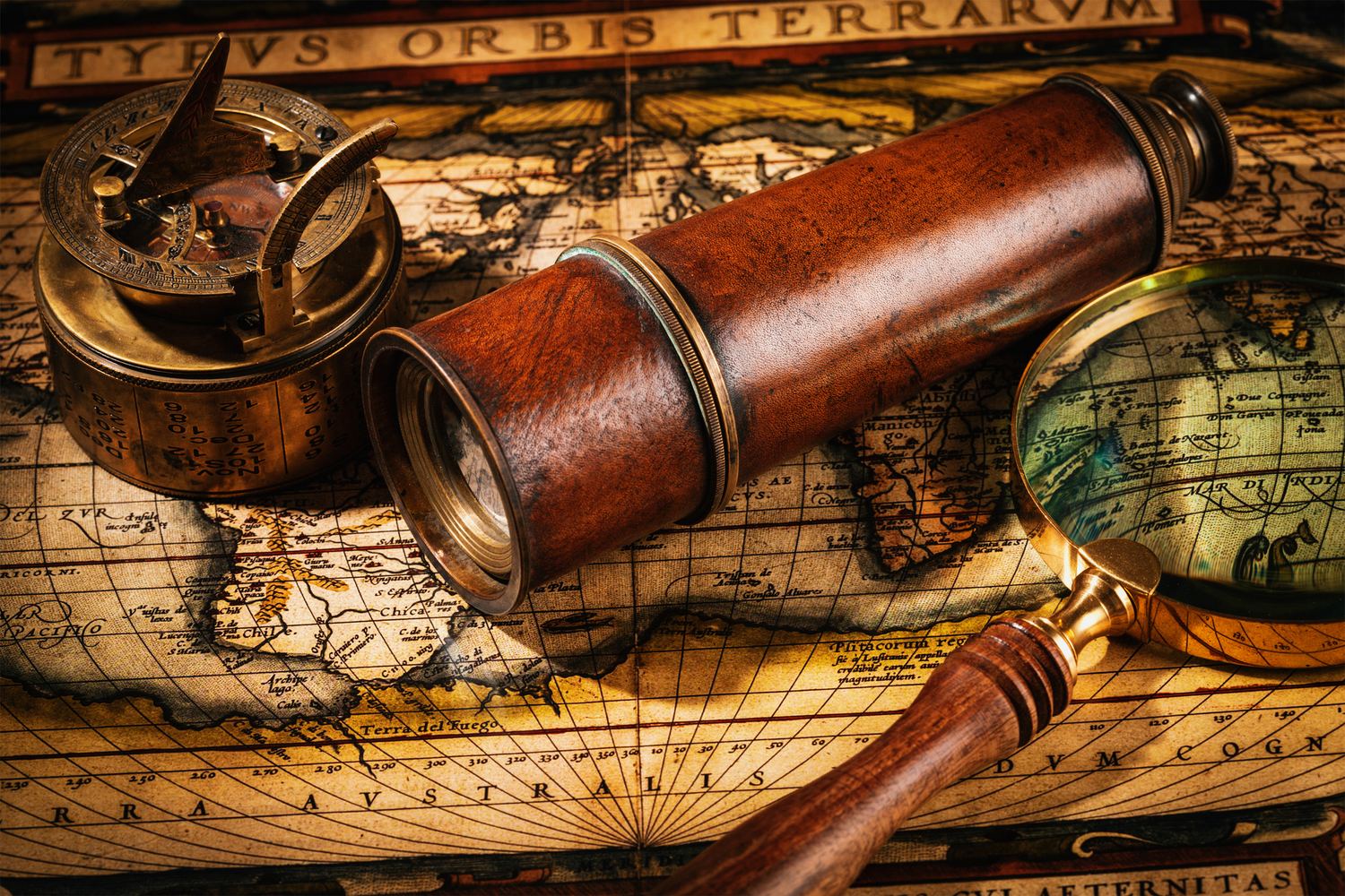 An antique telescope, compass and magnifier resting on a period map